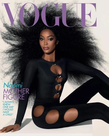 Naomi Campbell poses on a magazine cover in a black catsuit with circular cutouts, against a gradient white background. Big hair, close-up.