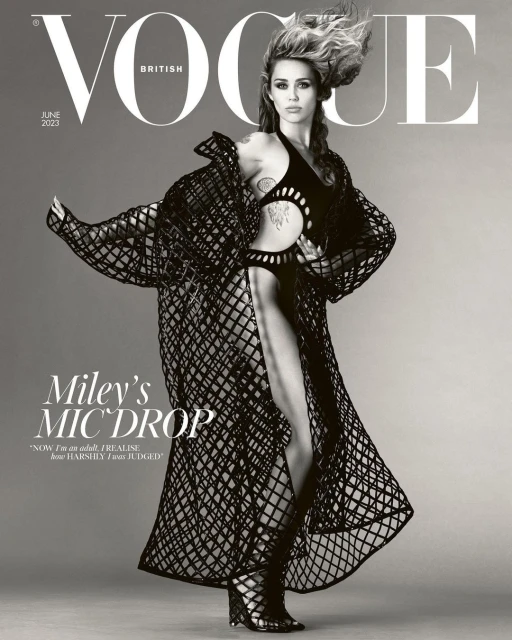 Miley Cyrus on the cover of British Vogue June 2023, wearing a black cut-out bodysuit and matching net-like long coat and gladiator heels.