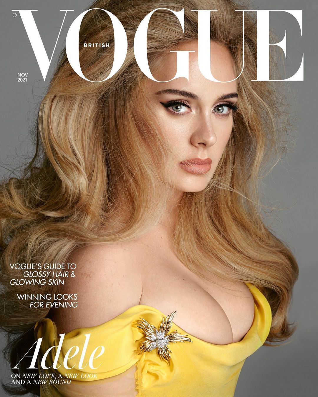British Vogue cover featuring Adele with long blonde hair, wearing a yellow dress and a star-shaped brooch, against a gray background.