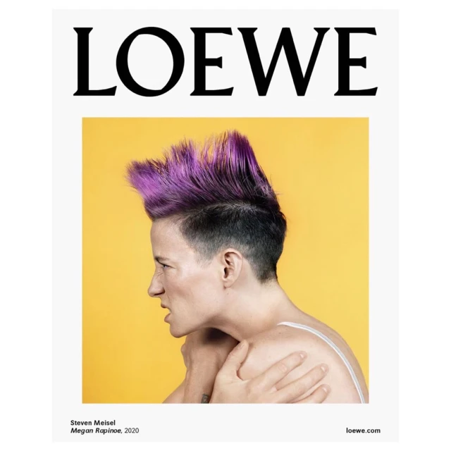Fashion portrait of a woman with purple hair against a yellow backdrop, promoting Loewe, a fashion brand, in a studio setting.