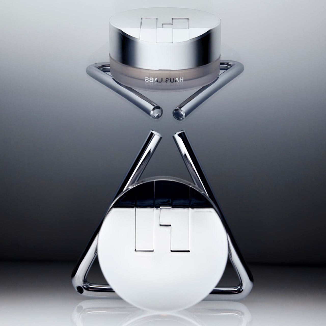 Cosmetic product shot of a Hyaluronic Acid moisturizing snow cushion compact sitting on a chrome display stand against a gradient background.