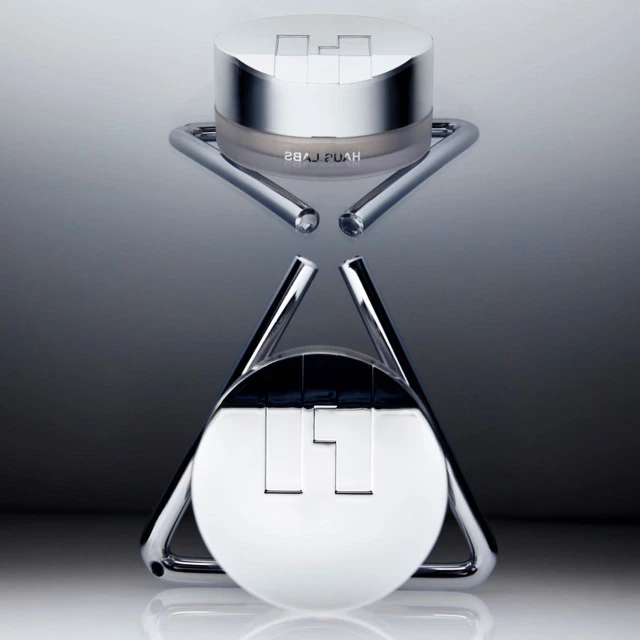Cosmetic product shot of a Hyaluronic Acid moisturizing snow cushion compact sitting on a chrome display stand against a gradient background.