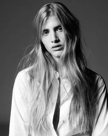 Black and white portrait of a long haired model wearing a button up shirt against a dark background