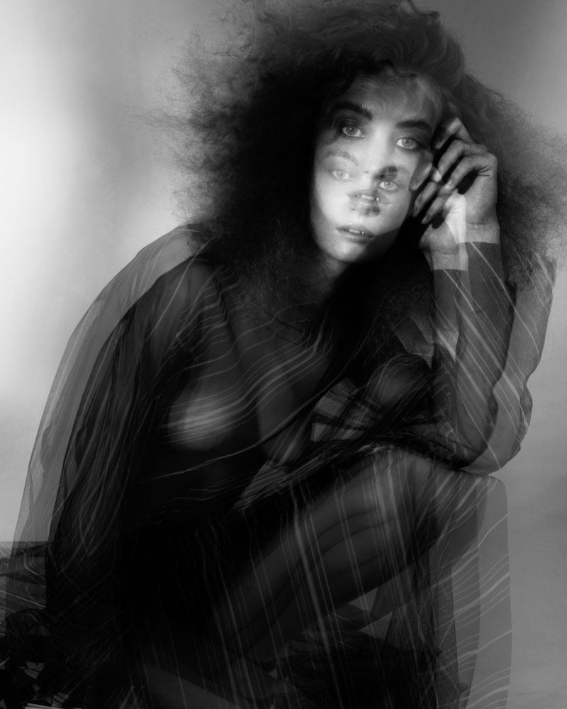 Monochrome image of a woman with flowing hair, overlaid with a double exposure effect, creating a surreal, artistic portrait.
