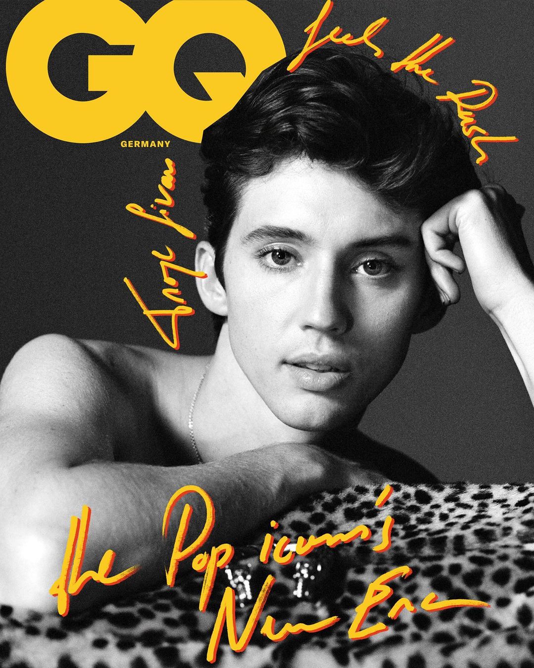 GQ magazine cover featuring a young man with dark hair, resting his head on his hand and posing on a leopard print surface.