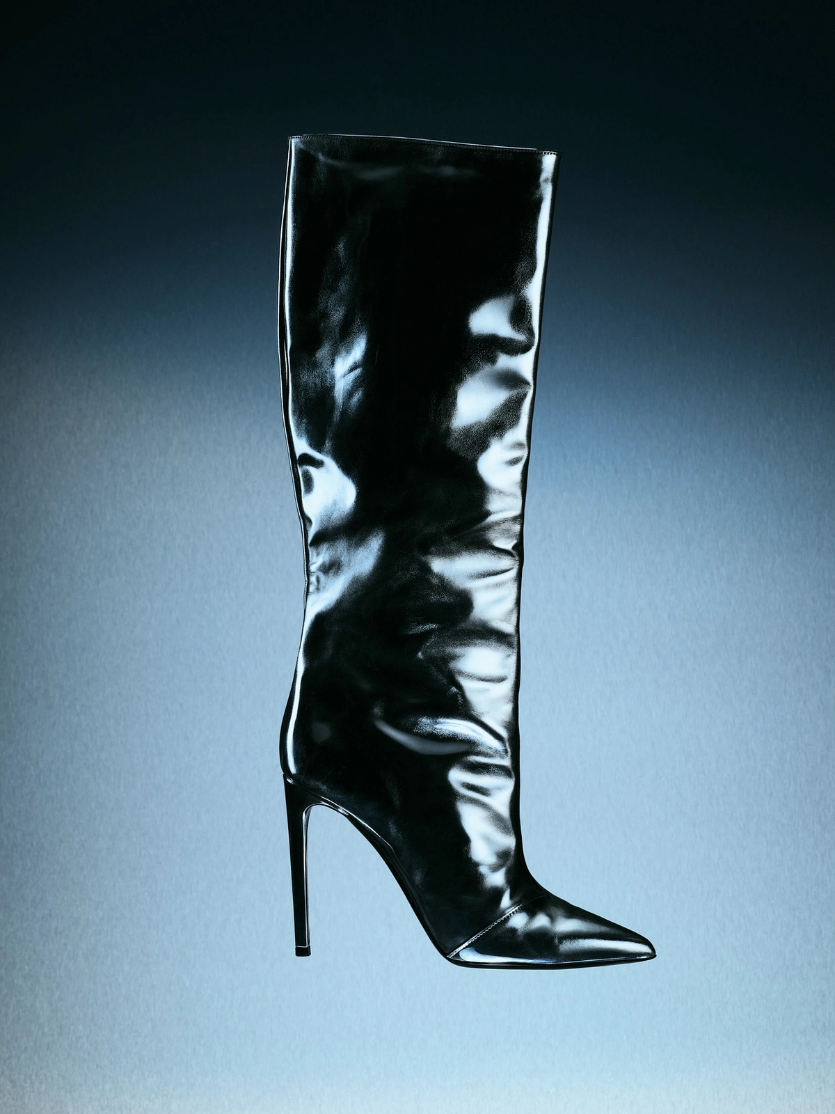 Glossy black high-heeled boot with a pointed toe displayed vertically against a gradient blue background