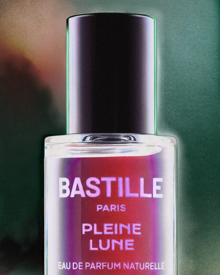 Close-up of Bastille Pleine Lune perfume bottle with black cap against a textured gradient background by Caroline Pusset.