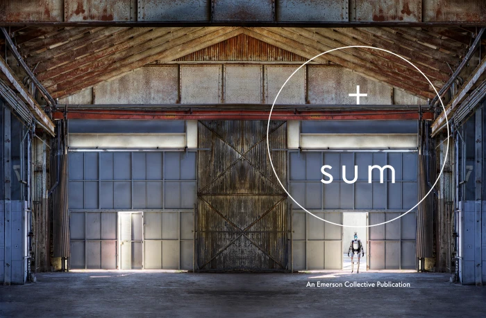 Symmetrical view inside a large industrial warehouse with a small humanoid robot standing in the doorway, created by Preston Chaplin.