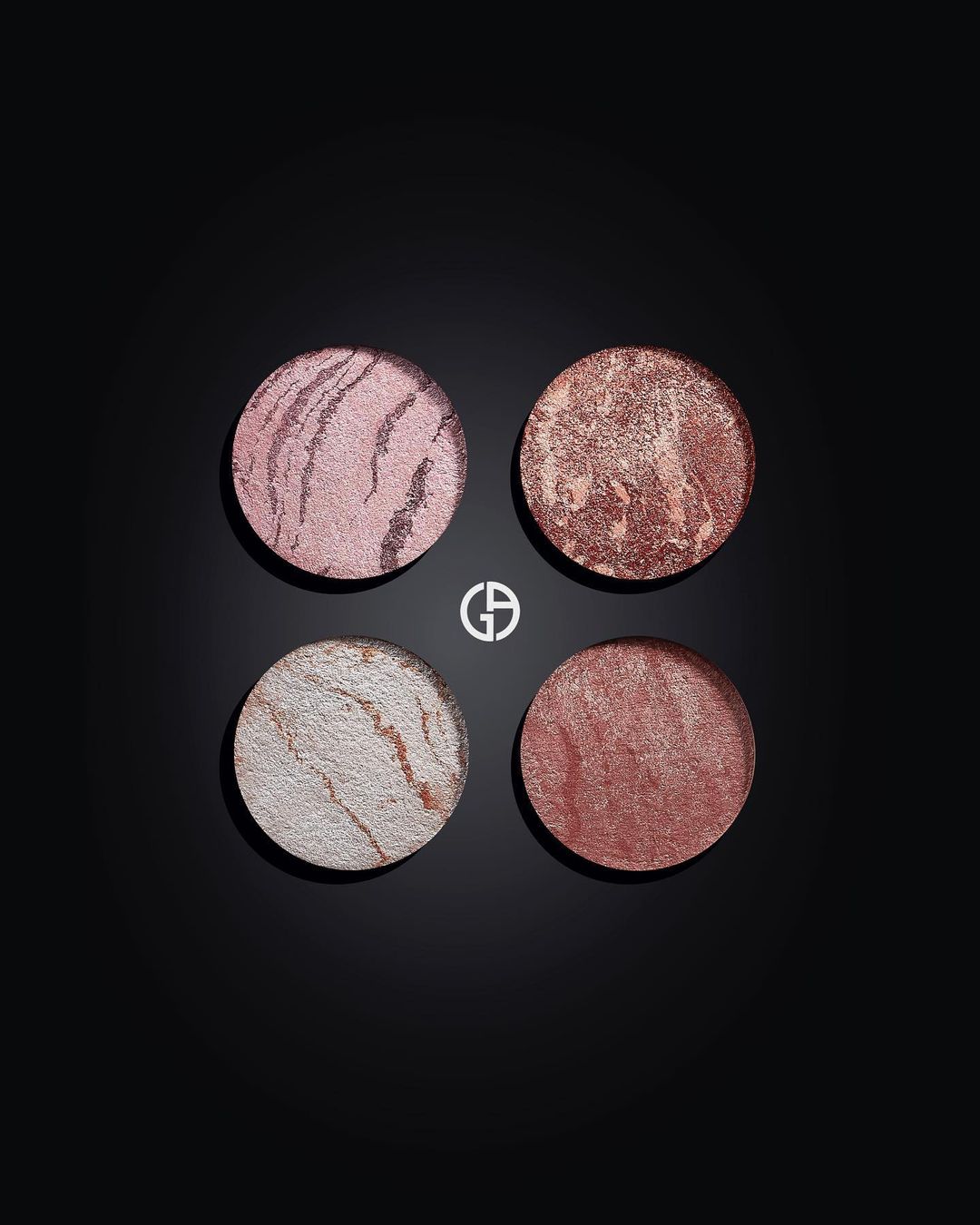 Four round Giorgio Armani beauty products in pink, bronze, and white tones displayed on a black surface, highlighting makeup textures.