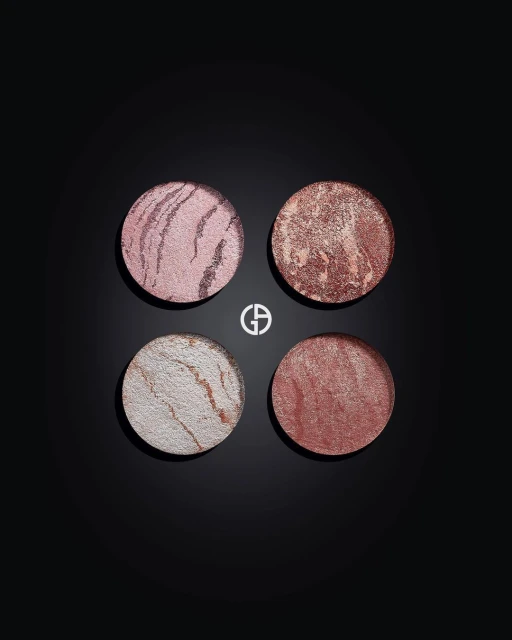 Four round Giorgio Armani beauty products in pink, bronze, and white tones displayed on a black surface, highlighting makeup textures.