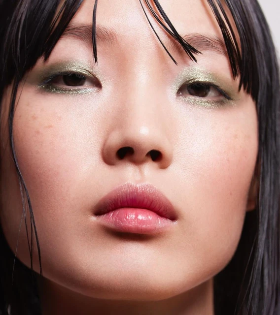 Close-up of an Asian adult female with green eyeshadow, black hair, and pink lips. Beauty shot for makeup and cosmetics.