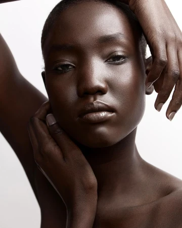 Close-up beauty portrait of a Black woman with hands framing her face against a white background