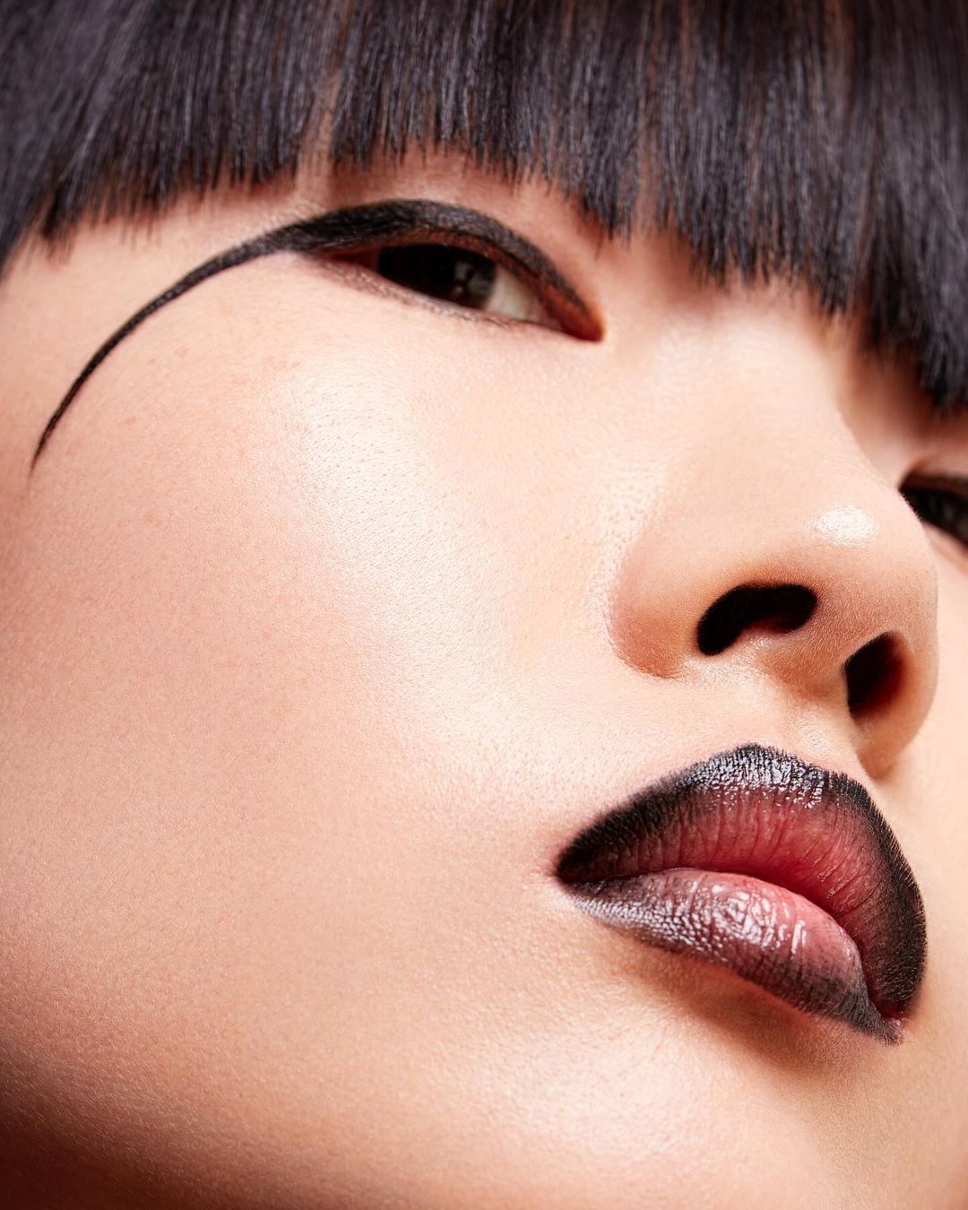 Close-up portrait of a model with heavy black graphic eyeliner and dark gradient lips photographed by Studio Wonderland in Paris.