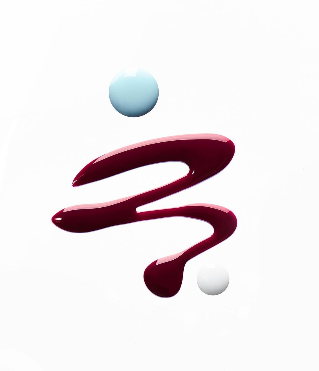 Swirls of glossy red and blue nail polish against a white background create an abstract beauty aesthetic with a modern, minimalist feel.