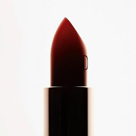 Close-up macro shot of a dark red lipstick bullet against a bright white seamless background