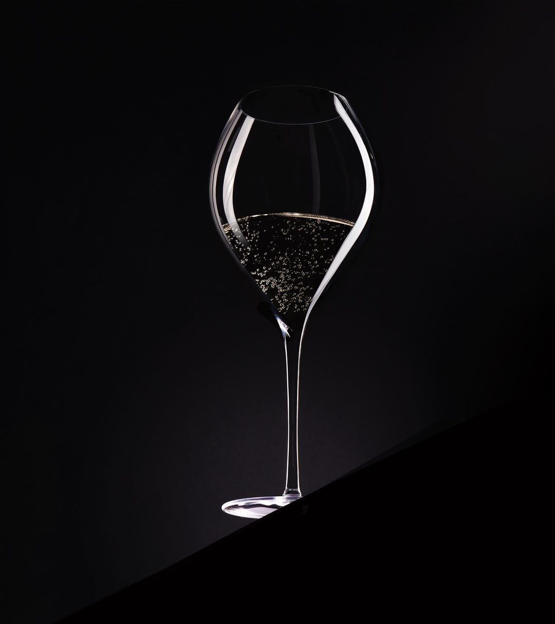 Elegant champagne flute filled with sparkling champagne on a dark surface and black background in a photo studio setting.