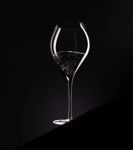 Elegant champagne flute filled with sparkling champagne on a dark surface and black background in a photo studio setting.