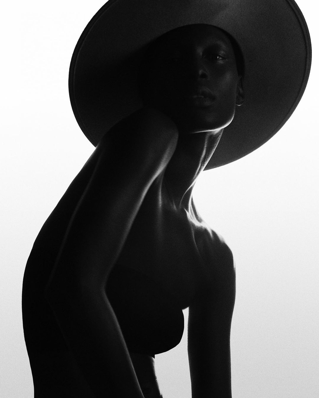 Model in wide-brimmed hat captured in dramatic silhouette against a bright white background by Studio Wonderland.