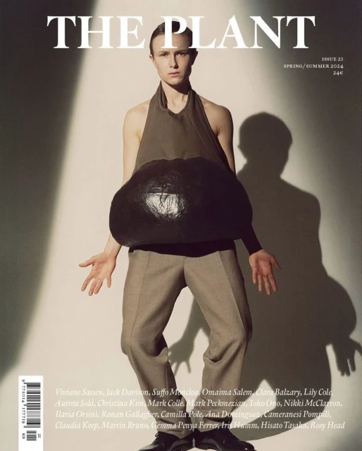 Magazine cover featuring a model wearing a halter top and trousers, posing with a large, black sculptural object in front of a white background.