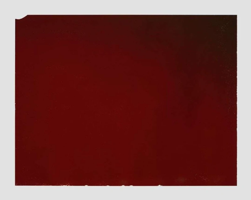 Solid maroon color fills the frame, creating a minimalist composition with subtle tonal variations and a slightly textured surface.