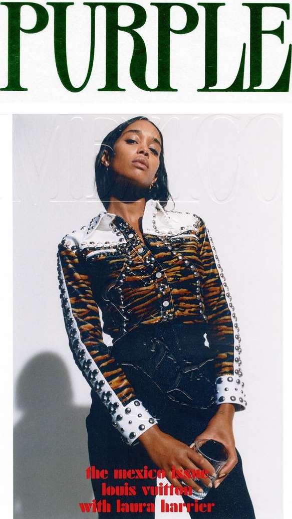 Portrait of a woman holding a glass in a studio setting wearing a jacket against a white backdrop for a magazine cover.