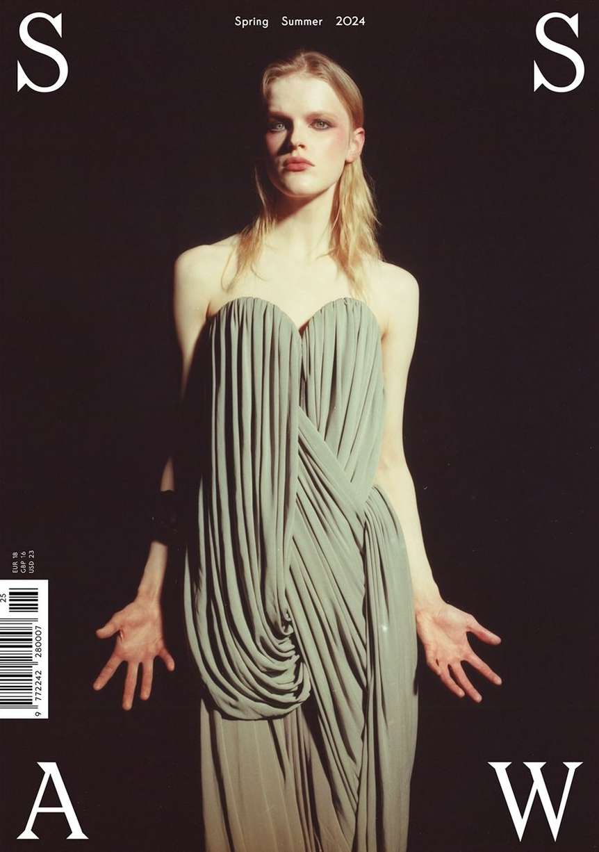 Fashion magazine cover featuring a model in an elegant grey dress against a dark background, with overlaid magazine title text and barcode.