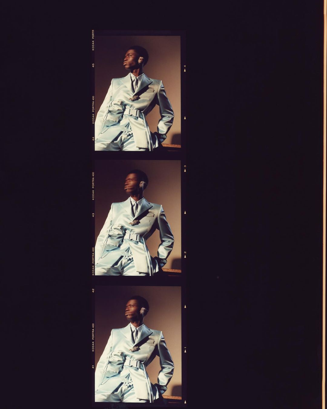 Three-panel view of a Black male model in a light blue suit, indoor studio setting, posing and looking to the side.