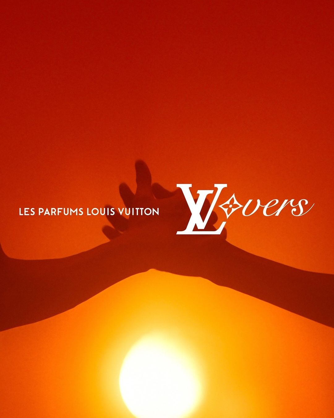 Louis Vuitton Lovers perfume advertisement featuring two hands reaching towards the sun, set against a warm orange background.