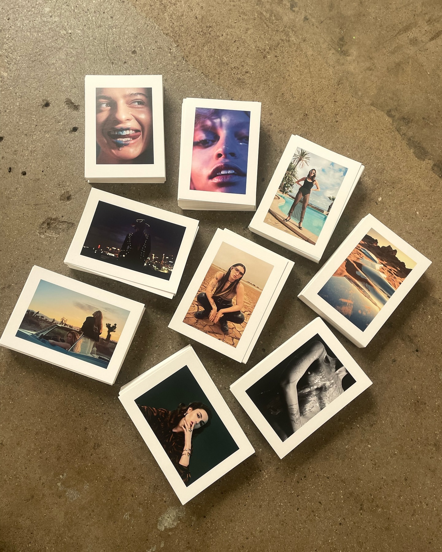 Collection of small photographic prints showcasing diverse portraits, landscapes, and figures arranged on a neutral surface.