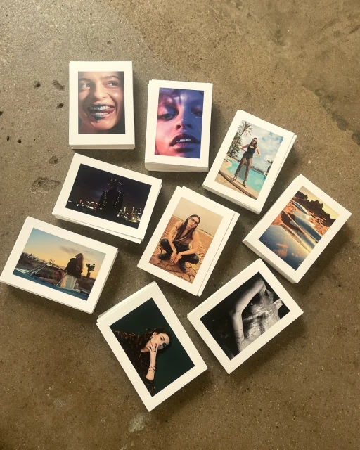 Collection of small photographic prints showcasing diverse portraits, landscapes, and figures arranged on a neutral surface.