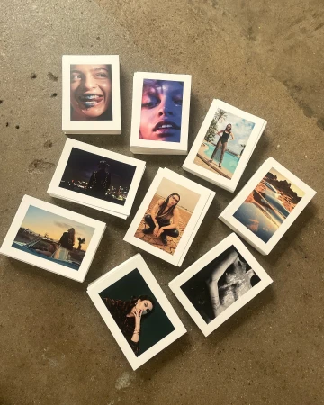 Collection of small photographic prints showcasing diverse portraits, landscapes, and figures arranged on a neutral surface.