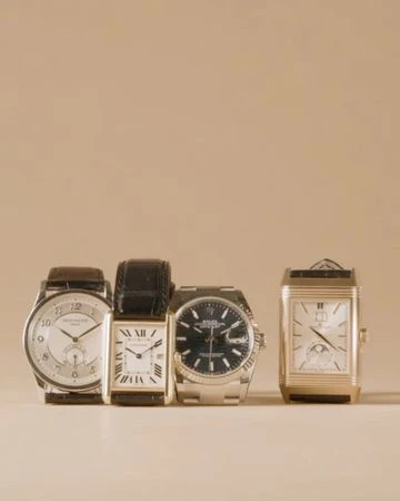 Close-up studio shot of four diverse wristwatches with leather and metal bands arranged in a row against a neutral background.