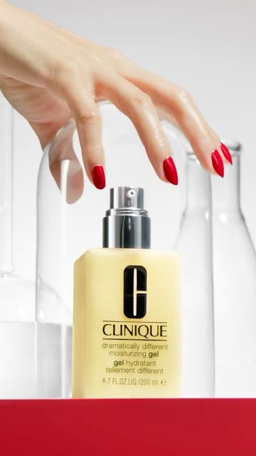 Close-up of Clinique moisturizing gel with a woman's hand on top. The background features white and clear bottles in a beauty shot.