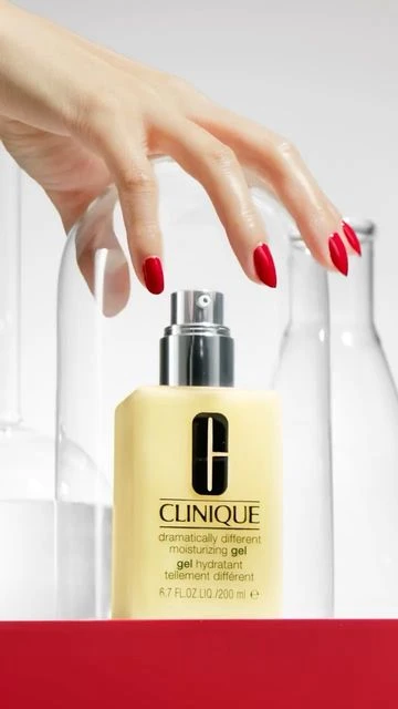 Close-up of Clinique moisturizing gel with a woman's hand on top. The background features white and clear bottles in a beauty shot.