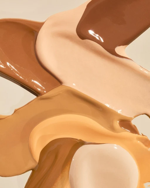Abstract close-up of light-to-dark foundation swatches in beige, tan, and brown tones, glossy texture, beauty concept.