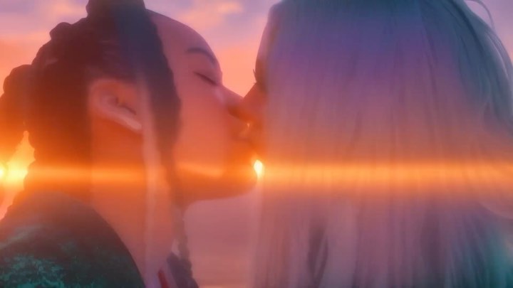 Close-up of two individuals in a romantic embrace, faces close together, with a soft focus and warm, orange and purple color grading.
