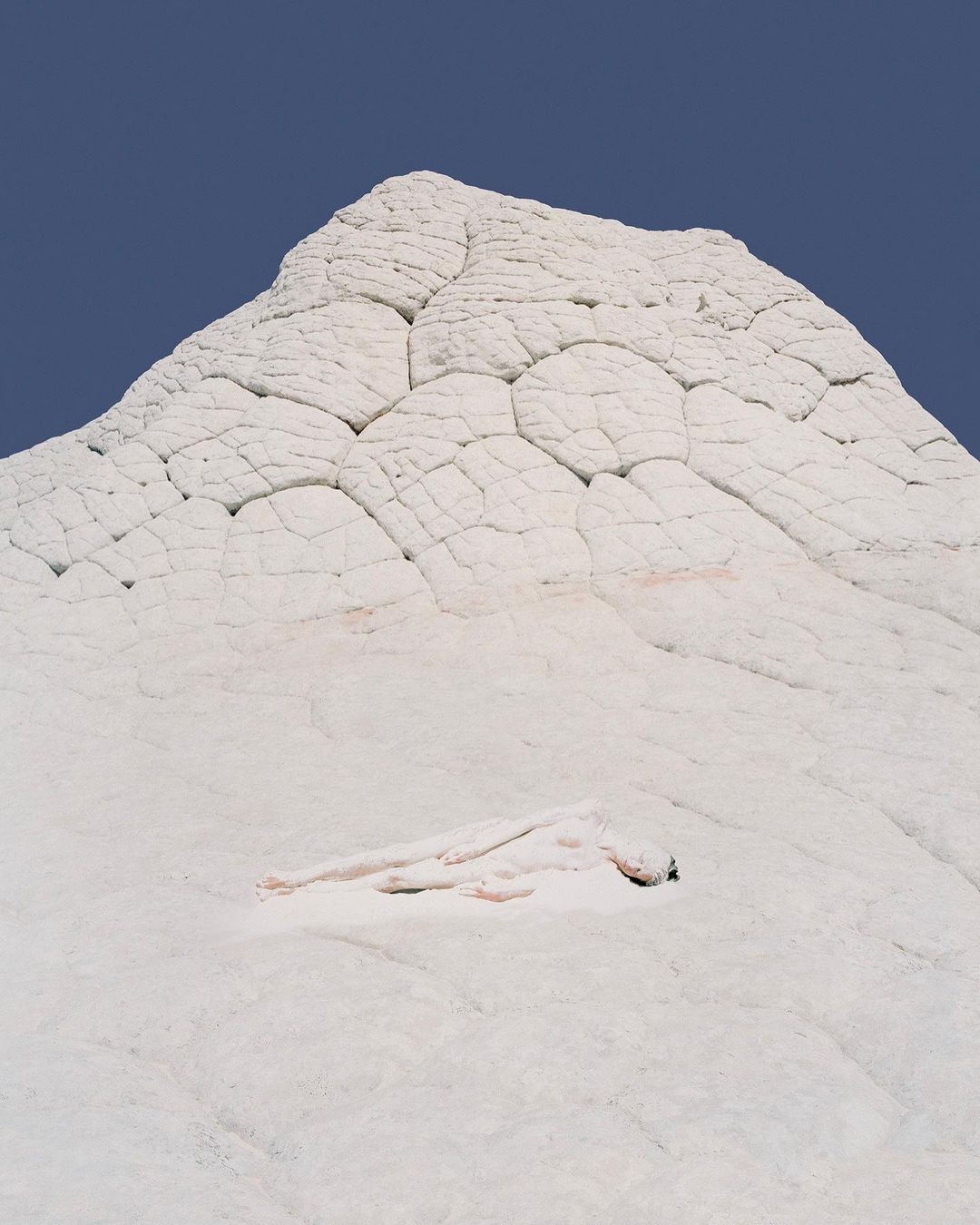 White rock formation against a blue sky, featuring unique textures and patterns, creating a natural and stark landscape scene.