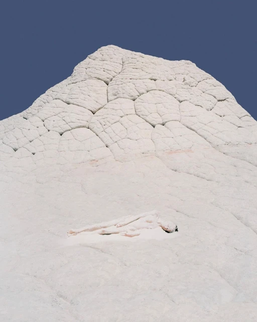 White rock formation against a blue sky, featuring unique textures and patterns, creating a natural and stark landscape scene.