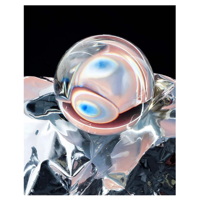 Abstract studio shot: clear crystal ball resting on crumpled silver foil, set against a black backdrop, showcasing reflections.