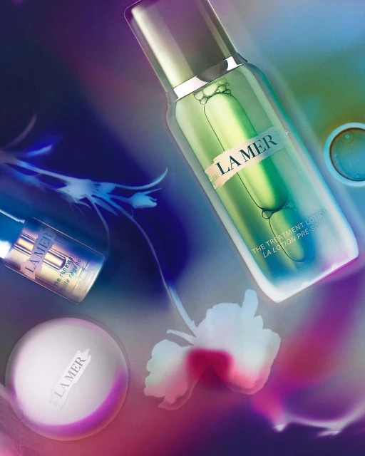 La Mer skincare products on a multicolored background with floral accents, featuring lotion, cream, and essence in an artistic composition.