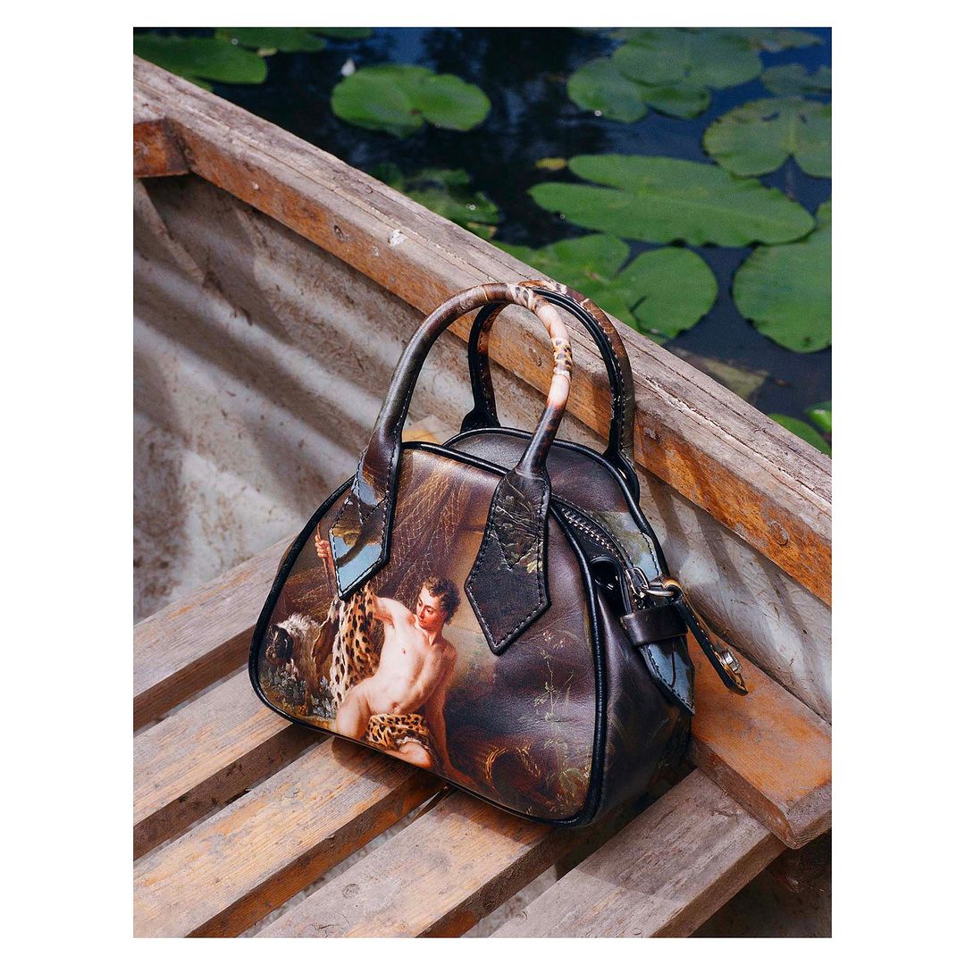 Handbag with a classic art image print on wooden slats against a background of water with lily pads creating a unique still life.