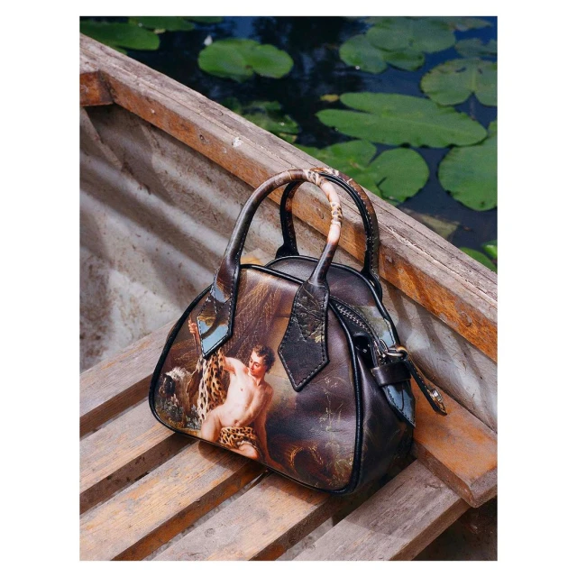 Handbag with a classic art image print on wooden slats against a background of water with lily pads creating a unique still life.