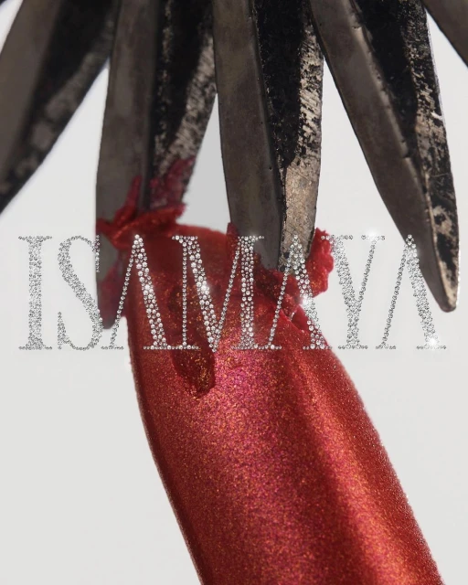 Macro shot of metal tweezers holding a shimmery red cosmetic product against a white background in a beauty or fashion context.