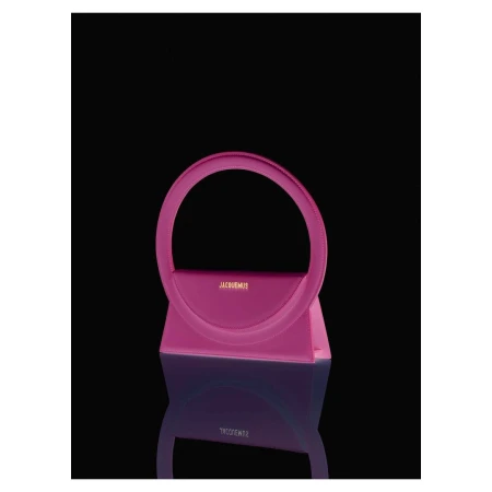 Stylish pink handbag with a unique circular handle and reflective surface against a dark backdrop. Fashion accessory.