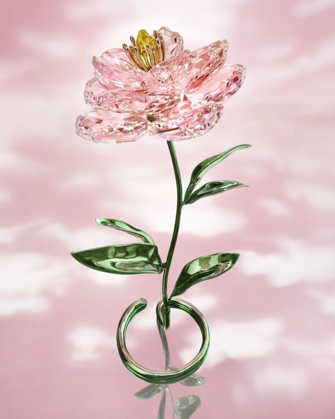 Crystal flower sculpture against a pink and white cloud-like background. The flower is pink with a gold center and green leaves.