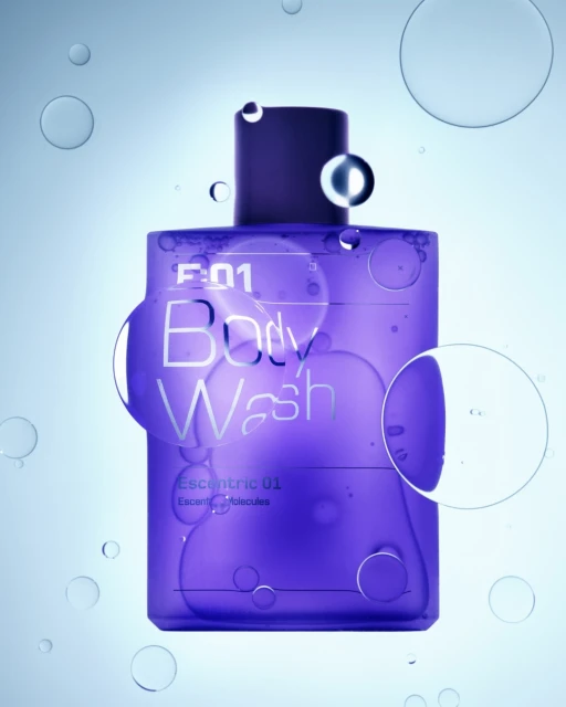 A bottle of purple body wash is surrounded by translucent spheres of varying sizes against a light blue background in a product shot.