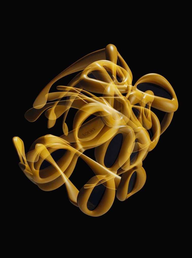 Abstract sculpture in yellow and black on black background. The sculpture's form is flowing, complex, and organic.