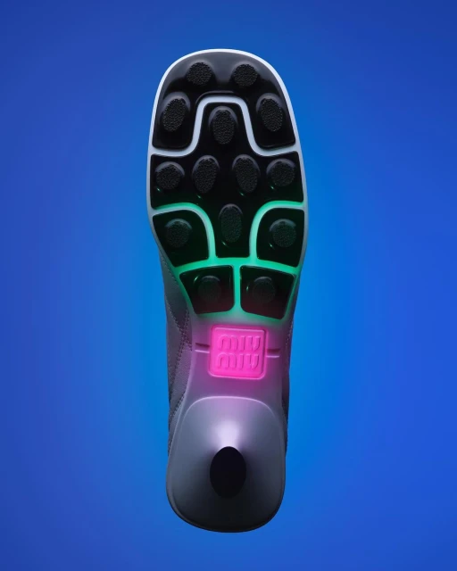 Elevated view of a single gray, black, white, green, and pink sport shoe on a blue background showcases its patterned sole design.