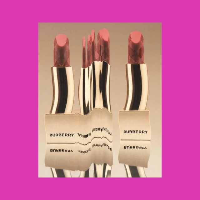 Three Burberry lipsticks are displayed, with a distorted reflection of one, set against a light gradient background and a pink square.