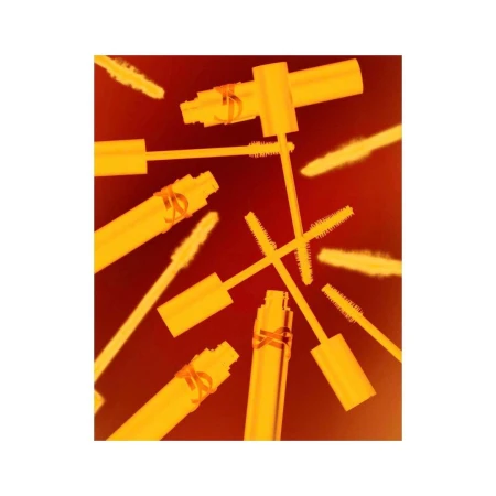 Close-up of yellow mascara tubes with wands on a red background. Cosmetic product shot for beauty, fashion, or promotional use.